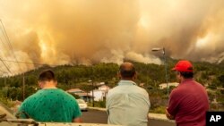 Locals look at a burning forest fire, near Puntagorda on the Canary Island of La Palma, July 15, 2023. The fire coincides with a heatwave that is hitting southern Europe.