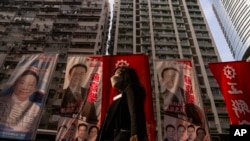 A pedestrian walks past banners promoting candidates for upcoming district council elections in Hong Kong, Dec. 4, 2023.