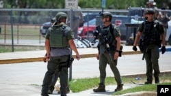 FILE - Police officers stand outside Robb Elementary School in Uvalde, Texas, after a shooting on May 24, 2022.