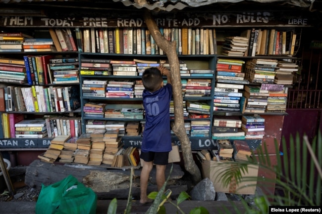 A boy picks out a book at Hernando Guanlao's home library in Makati, a metro area of Manila, Philippines, Feb. 7, 2024. (REUTERS/Eloisa Lopez)