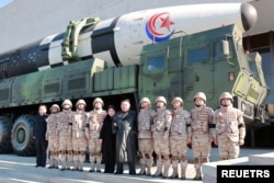 Pemimpin Korea Utara Kim Jong Un dan putrinya menghadiri sesi foto bersama para ilmuwan, insinyur, pejabat militer, dan pihak lain yang terlibat dalam uji coba rudal balistik antarbenua (ICBM) Hwasong-17 yang baru pada 2022. (Foto: KCNA via REUTERS)