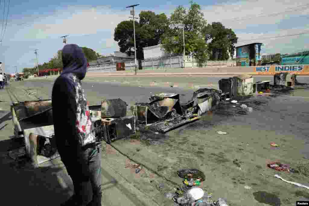 Un hombre camina cerca de una barricada consumida por el fuego mientras Haití continúa en estado de emergencia por las acciones de los grupos criminales. Visto en Puerto Príncipe, Haití, 6 de marzo de 2024.&nbsp;