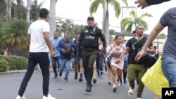 La policía evacua al personal de la estación de televisión pública TC después de que un grupo de hombres armados irrumpiera en su set durante una transmisión en vivo, en Guayaquil, Ecuador, el martes 9 de enero de 2024.