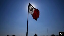 FILE - A Mexican flag waves in Mexico City's main square at sunrise, April 24, 2023. Mexican authorities said a bus crashed in Mexico on Friday, killing 24 and injuring five.