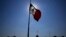 FILE - A Mexican flag waves in front of The National Palace, the office of the president, in Mexico City's main square, the Zocalo, at sunrise, April 24, 2023.