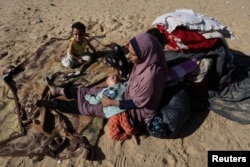 A woman sits with children outside, as displaced Palestinians, who fled their houses due to Israeli strike, shelter in a camp in Rafah, in the southern Gaza Strip, Dec. 6, 2023.
