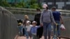 FILE - Women wearing face masks walk with masked children in Beijing, May 21, 2023.