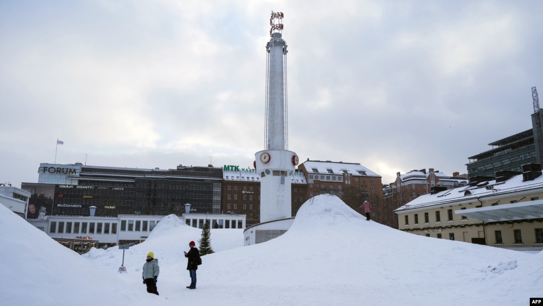 Orang-orang berdiri di area yang tertutup salju di ibu kota Finlandia, Helsinki, 3 Januari 2024, saat cuaca dingin melanda negara tersebut. Finlandia mengalami cuaca terdingin saat ini dengan suhu turun di bawah -32°C di wilayah utara Lapland. (Alessandro RAMPAZZO / AFP)