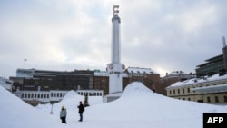 Orang-orang berdiri di area yang tertutup salju di ibu kota Finlandia, Helsinki, 3 Januari 2024, saat cuaca dingin melanda negara tersebut. Finlandia mengalami cuaca terdingin saat ini dengan suhu turun di bawah -32°C di wilayah utara Lapland. (Alessandro RAMPAZZO / AFP)