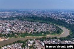 The Acre River winds through the city of Rio Branco, where smoke from fires fills the sky during a drought in Acre state, Brazil, Friday, Aug. 2, 2024. The city faces water shortages due to the river's low levels. (AP Photo/Marcos Vicentti)