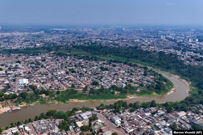 The Acre River winds through the city of Rio Branco, where smoke from fires fills the sky during a drought in Acre state, Brazil, Friday, Aug. 2, 2024. The city faces water shortages due to the river's low levels. (AP Photo/Marcos Vicentti)