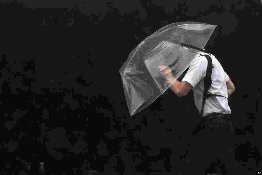 A person holds an umbrella against strong wind and rain as he walks on a street, in Tokyo, as a tropical storm was approaching.