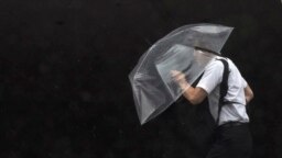 A person holds an umbrella against strong wind and rain as he walks on a street, in Tokyo, as a tropical storm was approaching.