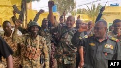 This picture released on the Sudanese Army's Facebook page on May 30, 2023, shows army chief Abdel Fattah al-Burhan cheering with soldiers as he visits some of their positions in Khartoum. 