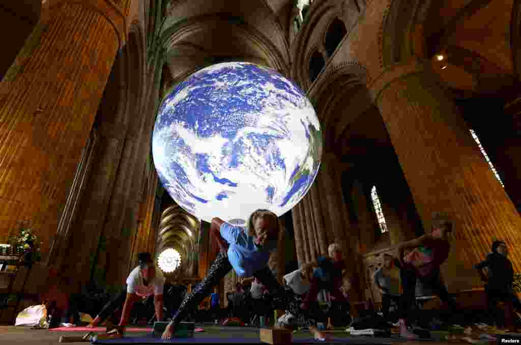 People participate in the Iyengar Yoga Class underneath Luke Jerram&#39;s Gaia artwork at Durham Cathedral in Durham, Britain.