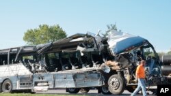 Seorang petugas membantu membereskan bus yang rusak akibat menabrak trailer di Highland. Illinois, pada 12 Juli 2023. (Foto: Christian Gooden/St. Louis Post-Dispatch via AP)