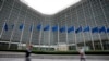 FILE - European Union flags wave in the wind as pedestrians walk by EU headquarters in Brussels, Sept. 20, 2023. The EU announced sanctions on 8 individuals and entities Monday.