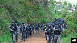 ARCHIVO-Esta foto publicada por la Policía Nacional de Ecuador muestra a policías armados llegando para allanar una mina de oro ilegal en Buenos Aires, Ecuador, el martes 2 de julio de 2019.