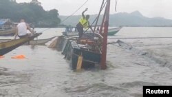 Seorang pria berdiri di atas kapal penumpang yang terbalik di Binangonan, provinsi Rizal, Filipina, 27 Juli 2023. (Philippine Coast Guard-videograb/Handout via REUTERS)