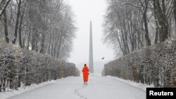 A woman walks in a snow-covered park during a first snowfall, amid Russia&#39;s attack in Ukraine, in Kyiv.