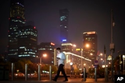 FILE - A man walks past the Central Business District in Beijing, July 15, 2024.