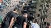 People gather outside of a residential building that according to local authorities was hit by debris from a destroyed Ukrainian missile in Kursk, Russia, Aug. 11, 2024. (Kommersant Photo/Anatoliy Zhdanov via Reuters)