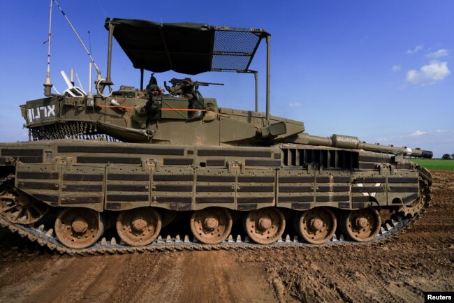 Seorang tentara Israel menunjuk ke kamera saat ia mengendarai tank di dekat perbatasan Israel-Gaza di Israel, 26 Januari 2024. (Foto: REUTERS/Alexandre Meneghini)