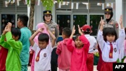 Polisi wanita dari Mapolrestabes Batam bersama siswi SD saat acara "trauma healing" karena banyak siswi yang menolak bersekolah usai bentrok antara warga dan aparat keamanan terkait rencana pemerintah mengembangkan sekolah, 18 September 2023. (Bay ISMOYO / AFP).