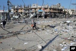 Palestinians walk through destruction by the Israeli bombardment in the Nusseirat refugee camp in Gaza Strip, Jan. 16, 2024.