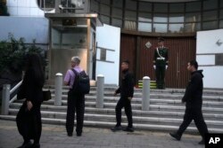 Chinese plainclothes security personnel approach a passerby outside the Israeli Embassy in Beijing, Oct. 13, 2023.