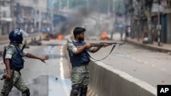 A policeman aims his weapon at protesters during protests against Prime Minister Sheikh Hasina and her government, in Dhaka, Bangladesh, Aug. 5, 2024.