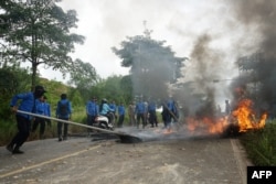 Petugas pemadam kebakaran memadamkan api di jalan yang dibuat oleh warga saat aksi protes di Tanjung Kertang, Pulau Rempang, 8 September 2023. (ANDARU / AFP)