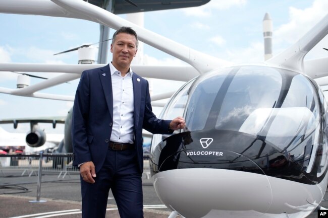 Volocopter CEO Dirk Hoke poses for a picture next to the Volocopter 2X, an electric vertical takeoff and landing multicopter, during the Paris Air Show in Le Bourget, north of Paris, France, Monday, June 19, 2023. (AP Photo/Lewis Joly)