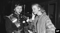 FILE - Actress Piper Laurie watches piper Thomas Gorrian of the Lovat Pipe Band before the premiere of a 3-D film, "King of the Khyber Rifles," in New York, Dec. 23, 1953.