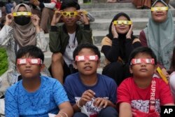 FILE - Youths wear protective glasses to watch an eclipse in Jakarta, Indonesia, April 20, 2023. An annular solar eclipse — better known as a ring of fire — will be visible over parts of the western U.S. and Central and South America on Oct. 14, 2023.