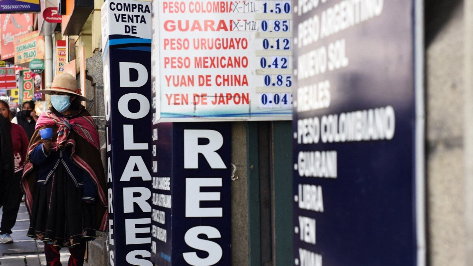 FILE - People walk near a currency exchange point, in La Paz, Bolivia, March 6, 2023. 