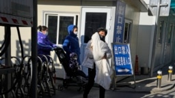 FILE - Seorang perempuan menggendong seorang anak saat mereka meninggalkan rumah sakit anak-anak di Beijing, Jumat, 24 November 2023. (AP/Ng Han Guan)