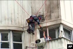 In this image taken from video, investigators inspect the building after a Ukrainian drone damaged an apartment building in Moscow, May 30, 2023.