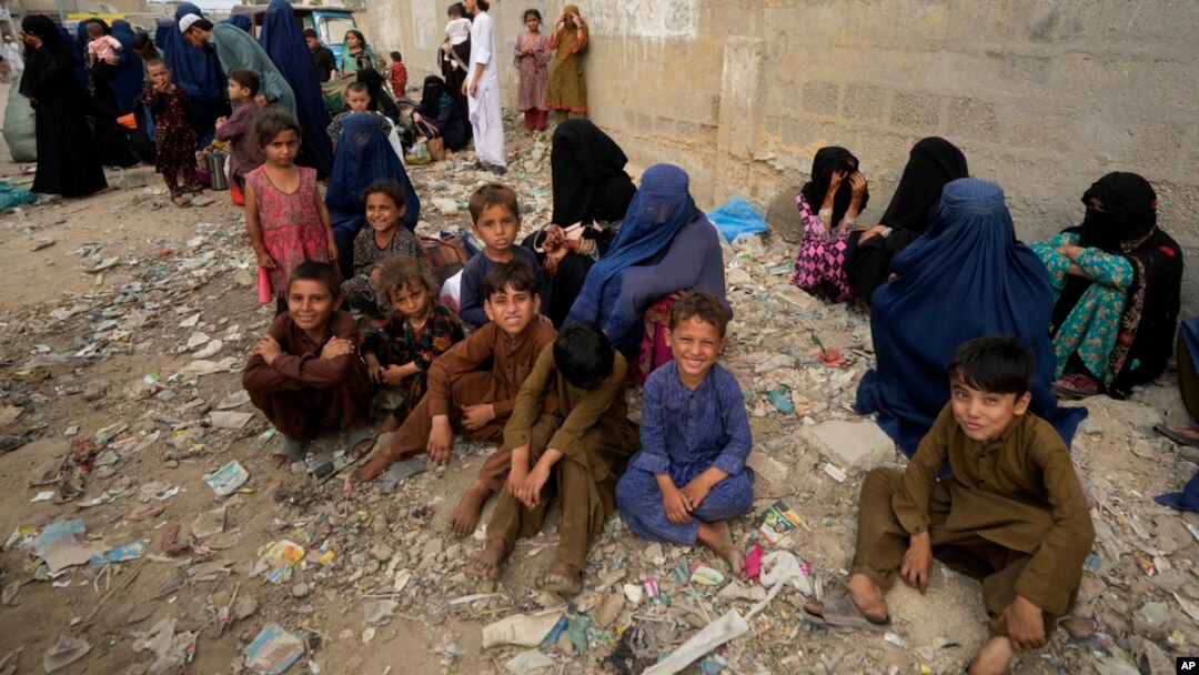 Afghan families wait to board into a bus to depart for their homeland, in Karachi, Pakistan, Oct. 6, 2023.