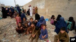 পাকিস্তানের করাচিতে আফগান পরিবারের সদস্যরা নিজ দেশে প্রত্যাবাসনের জন্য বাসে ওঠার জন্য অপেক্ষা করছে; ৬ অক্টোবর ২০২৩। 