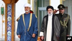 In this photo released by the office of the Iranian Presidency, Oman's Sultan Haitham bin Tariq Al Said, left, and Iranian President Ebrahim Raisi attend the official welcoming ceremony for Sultan Haitham at the Saadabad Palace in Tehran, May 28, 2023. 