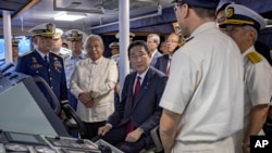 Japan's Prime Minister Fumio Kishida, center, sits on the bridge of a ship at the Philippine Coast Guard headquarters on Nov. 4, 2023, in Manila. Kishida was in the Philippines for talks about a potential defense pact.
