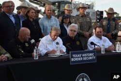 FILE - Gubernur Texas Greg Abbott menandatangani tiga rancangan undang-undang di lokasi pembangunan tembok perbatasan di Brownsville, Texas, 18 Desember 2023. (AP/Valerie Gonzalez, File)