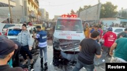 Palestinians check the damages after a convoy of ambulances was hit, at the entrance of Shifa hospital in Gaza City, Nov. 3, 2023