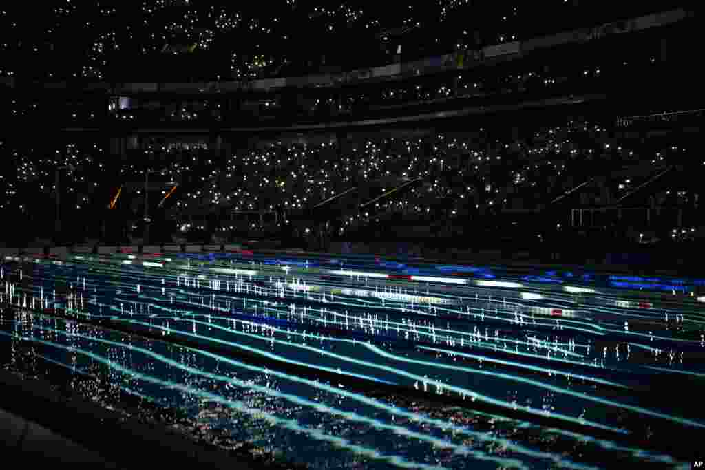 Spectators turn on their mobile phone flashlights before the heats swimming series begins during the 2024 Paralympics in Paris, France.