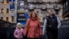 (FILE) Women and a child walk near a recruitment poster for the Azov Assault Brigade of the National Guard of Ukraine, amid Russia's attack on Ukraine, in Kyiv, Ukraine, November 8, 2023.