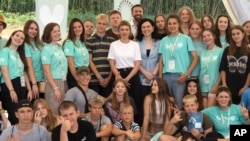 First lady Olena Zelenska, in white, poses for a photo during her visit to a rehabilitation camp for war-affected children, organized by the Voices of Children Charitable Foundation and financially supported by the Olena Zelenska Foundation, in Uzhhorod, Ukraine, Aug. 27, 2024.