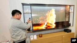 A show attendee examines the world's first transparent TV, the LG SIGNATURE OLED T 4K TV, at the LG Electronics booth during CES 2024 Tuesday, Jan. 9, 2024, in Las Vegas. (Jack Dempsey/AP Images for LG)