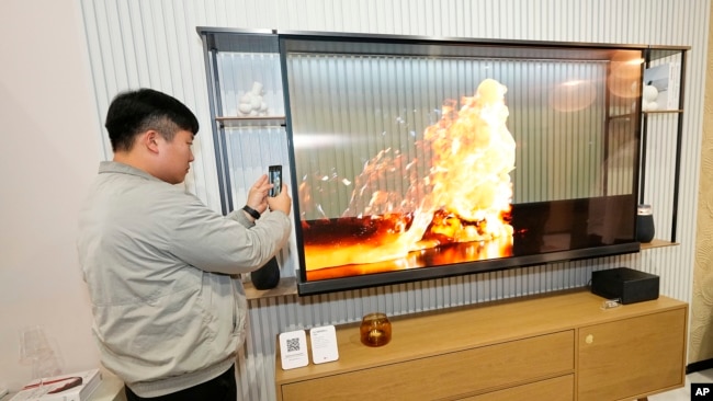 A show attendee examines the world's first transparent TV, the LG SIGNATURE OLED T 4K TV, at the LG Electronics booth during CES 2024 Tuesday, Jan. 9, 2024, in Las Vegas. (Jack Dempsey/AP Images for LG)