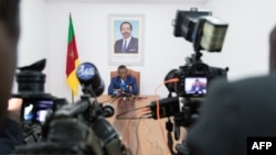 FILE - Cameroonian Prime Minister Joseph Dion Ngute speaks to journalists in Yaounde, Oct. 3, 2019. Ngute is sitting under a portrait of Cameroonian President Paul Biya who, now 91, may run for reelection next year.